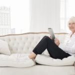 neat old woman sitting sofa with tablet scaled