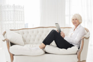 neat old woman sitting sofa with tablet scaled