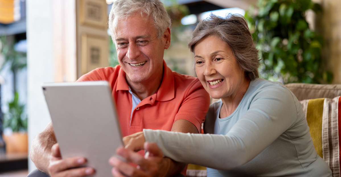 Adult child on a phone call looking at a calendar, representing long-distance support for aging parents.